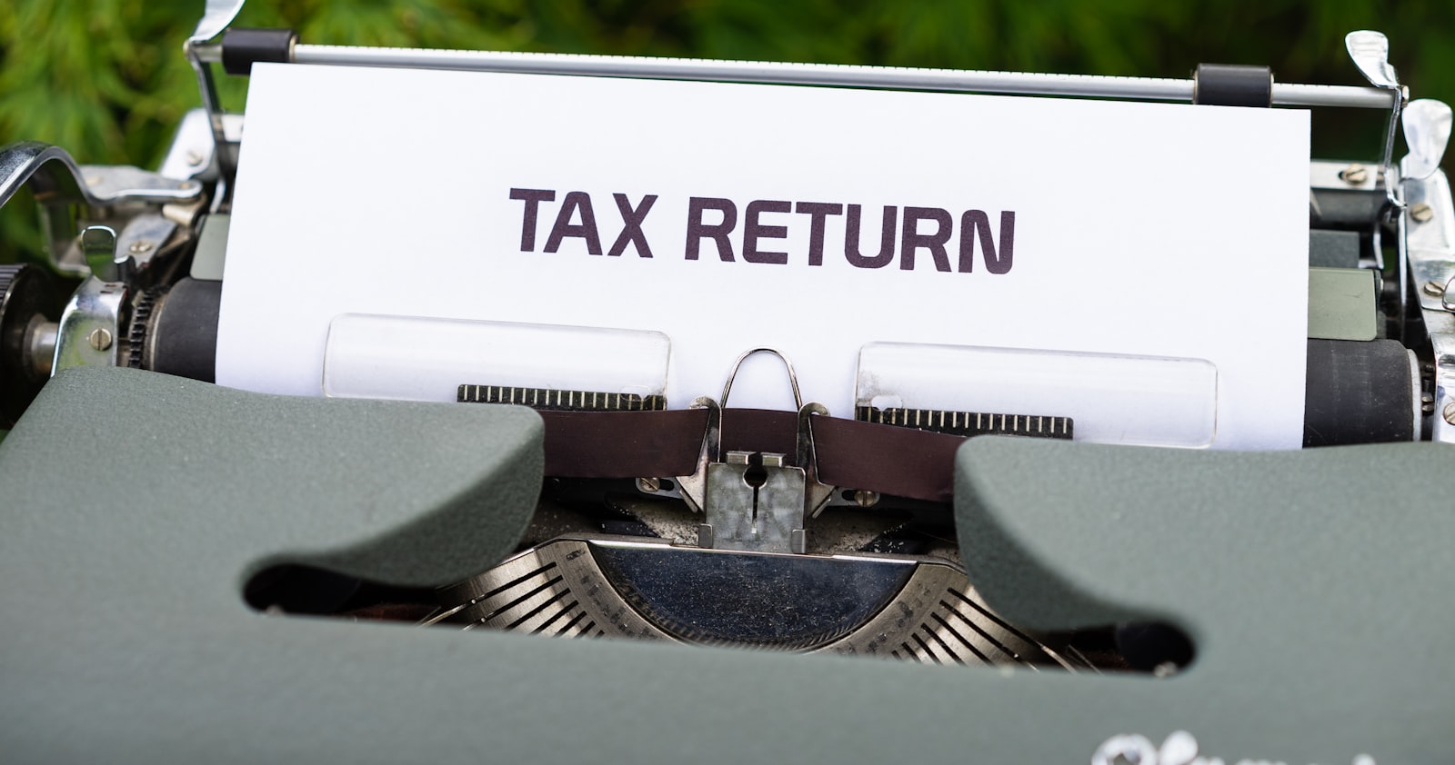 Nahaufnahme einer Schreibmaschine mit eingespanntem Blatt „Tax Return“ — Differenzbesteuerung beim Wohnmobil-Verkauf